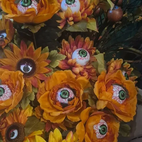 Halloween arrangement of artificial orange and yellow flowers with bloodshot eyeballs placed inside each blossom